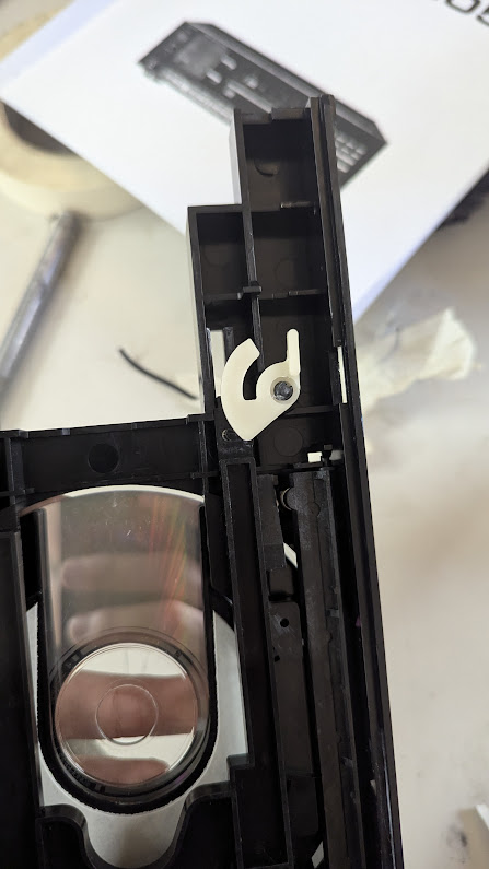 I seriously don't know how to describe this piece. It turns rotation into translation, and it's got a crescent shape. It's held on by hot glue at its center.