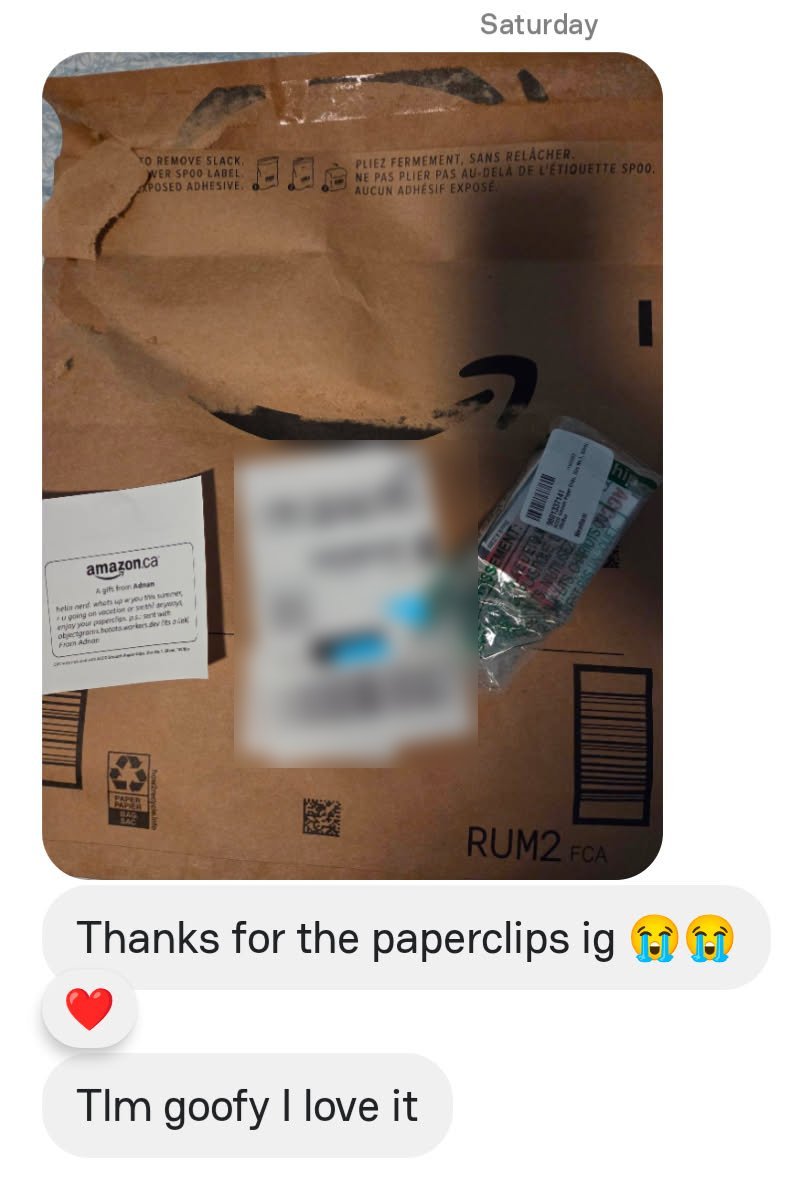 A chat screenshot: a photo of an opened Amazon envelope with a gift note from Adnan, the shipping label and a small bag of green paperclips, then the replies 'Thanks for the paperclips ig' with two crying-laughing faces, and 'Tlm goofy I love it'.